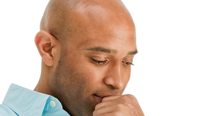 Black bald man in a button-down shirt considering his options for Micropigmentation Procedures