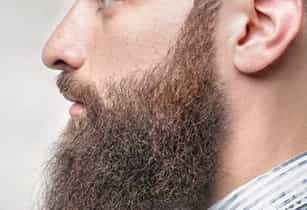 A man displays his full, bushy auburn beard after receiving treatment for facial hair in New Jersey